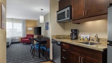 Cocina hotelera compacta con microondas, cafetera y lavabo.