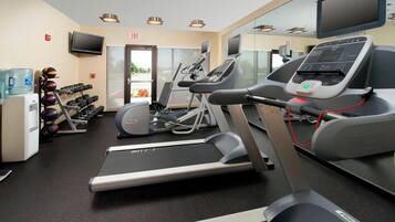 A gym with treadmills, elliptical machines, and free weights.