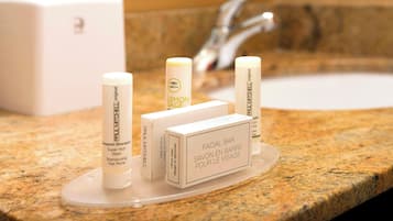 Una encimera de baño con dispensador de jabón facial y una caja etiquetada "FACIAL BAR SAVON EN BARRE POUR LE VISAGE".