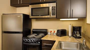 Una cocina compacta equipada con refrigerador, microondas, estufa, horno y pileta.