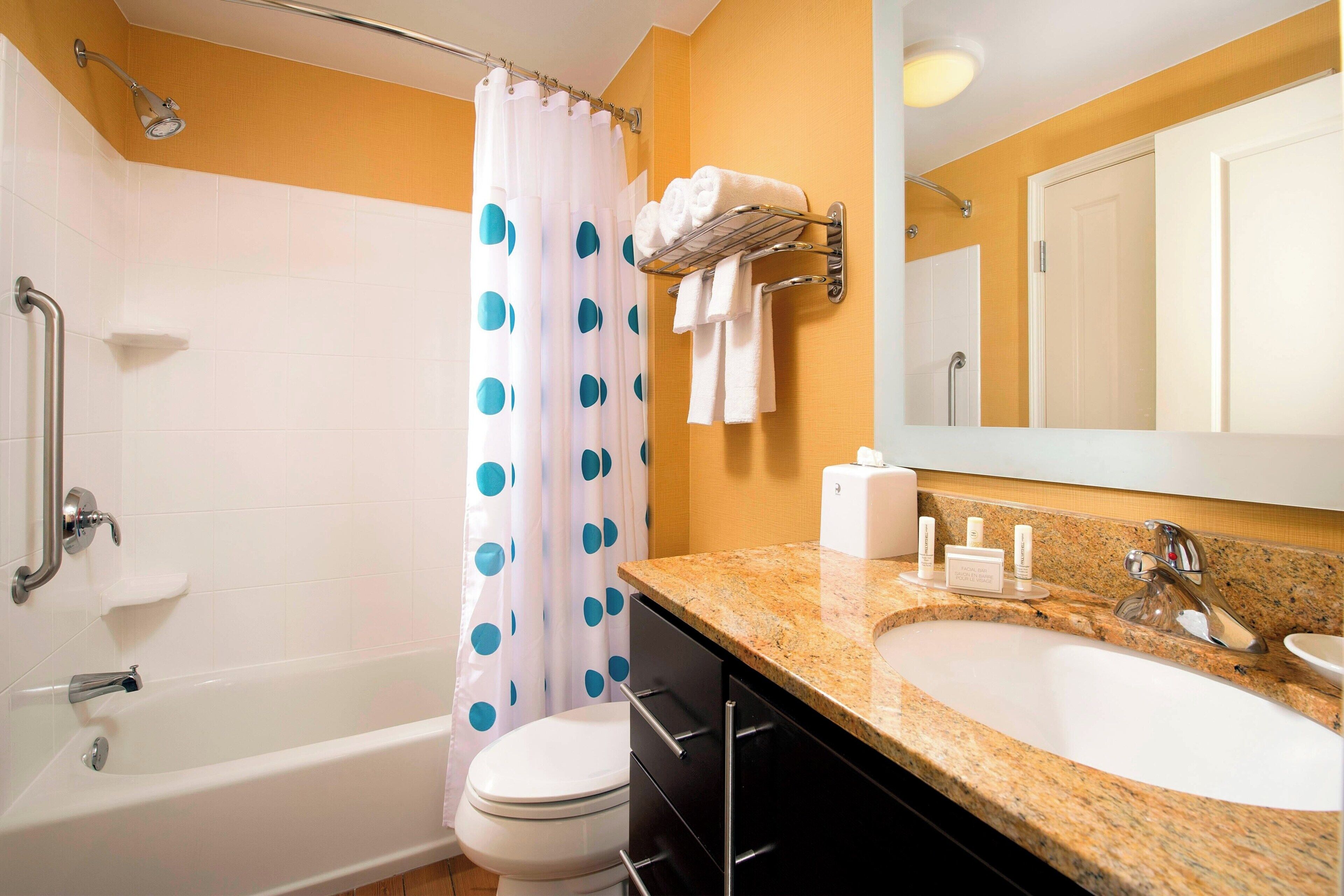 A bathroom with a bathtub, toilet, sink, and shower curtain.