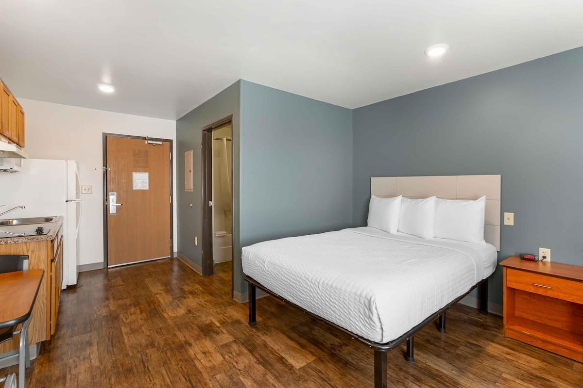 A bedroom with a bed, bedside table, and a small wooden nightstand.