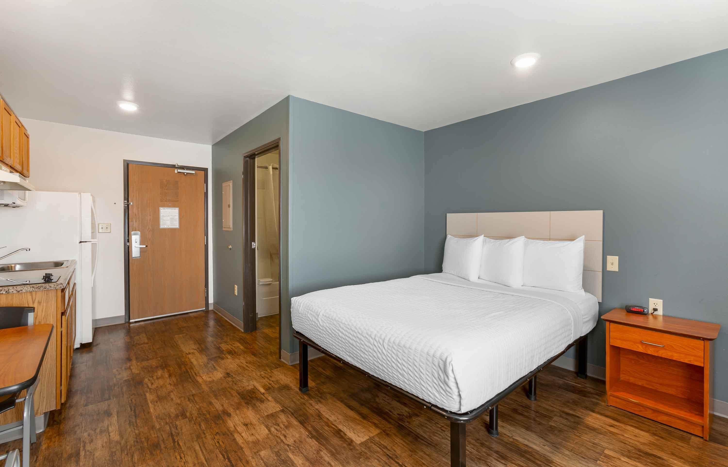 Un dormitorio con cama, mesita de noche y una pequeña mesita auxiliar de madera.