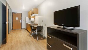 A compact hotel room with a kitchenette, a flat-screen TV, a desk with a chair, and a wardrobe. - Extended Stay America Select Suites - Phoenix - North (Phoenix)
