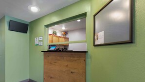 A reception desk with a laptop, framed certificates, and a wooden counter. - Extended Stay America Select Suites - Phoenix - North (Phoenix)