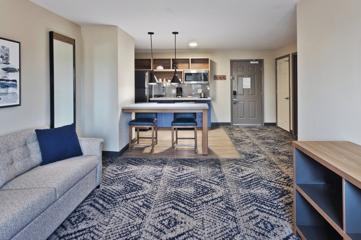 Una cocina moderna con barra, un sofá y una alfombra estampada.