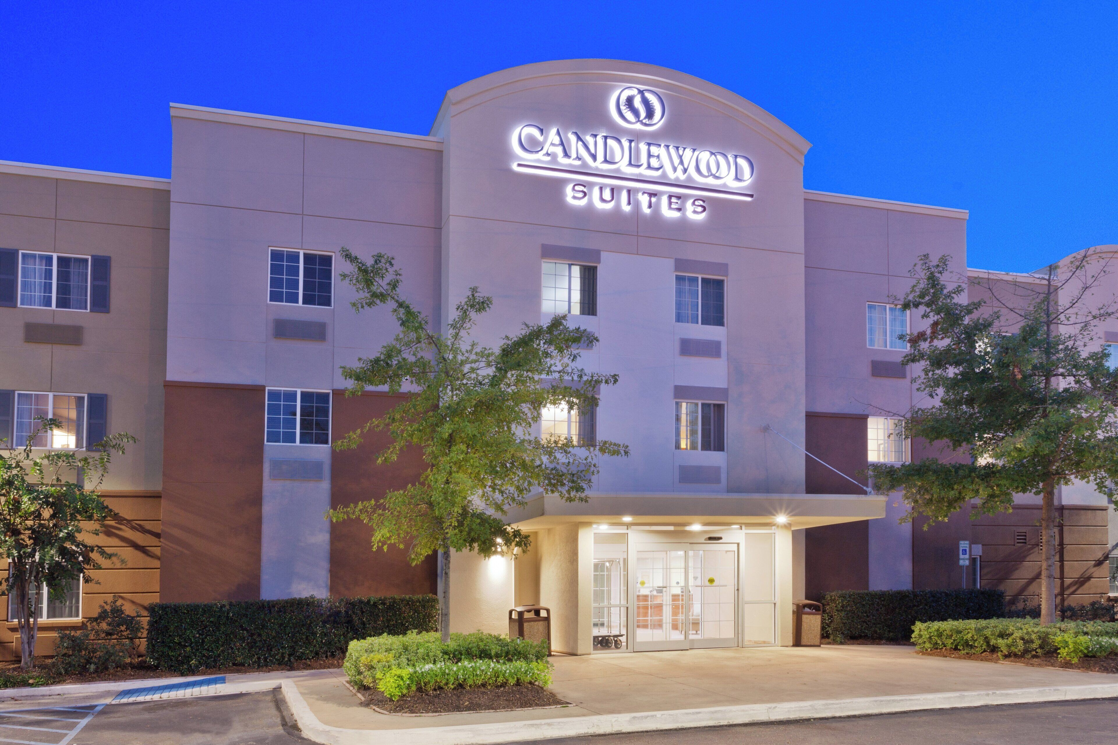 Un hotel con un letrero llamativo que dice 'CANDLEWOOD SUITES' y una entrada bien iluminada.