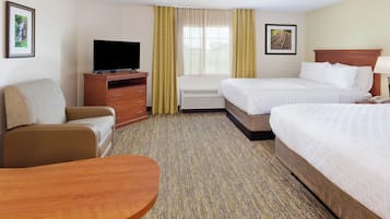 A hotel room with two beds, a TV, a desk, and a chair.