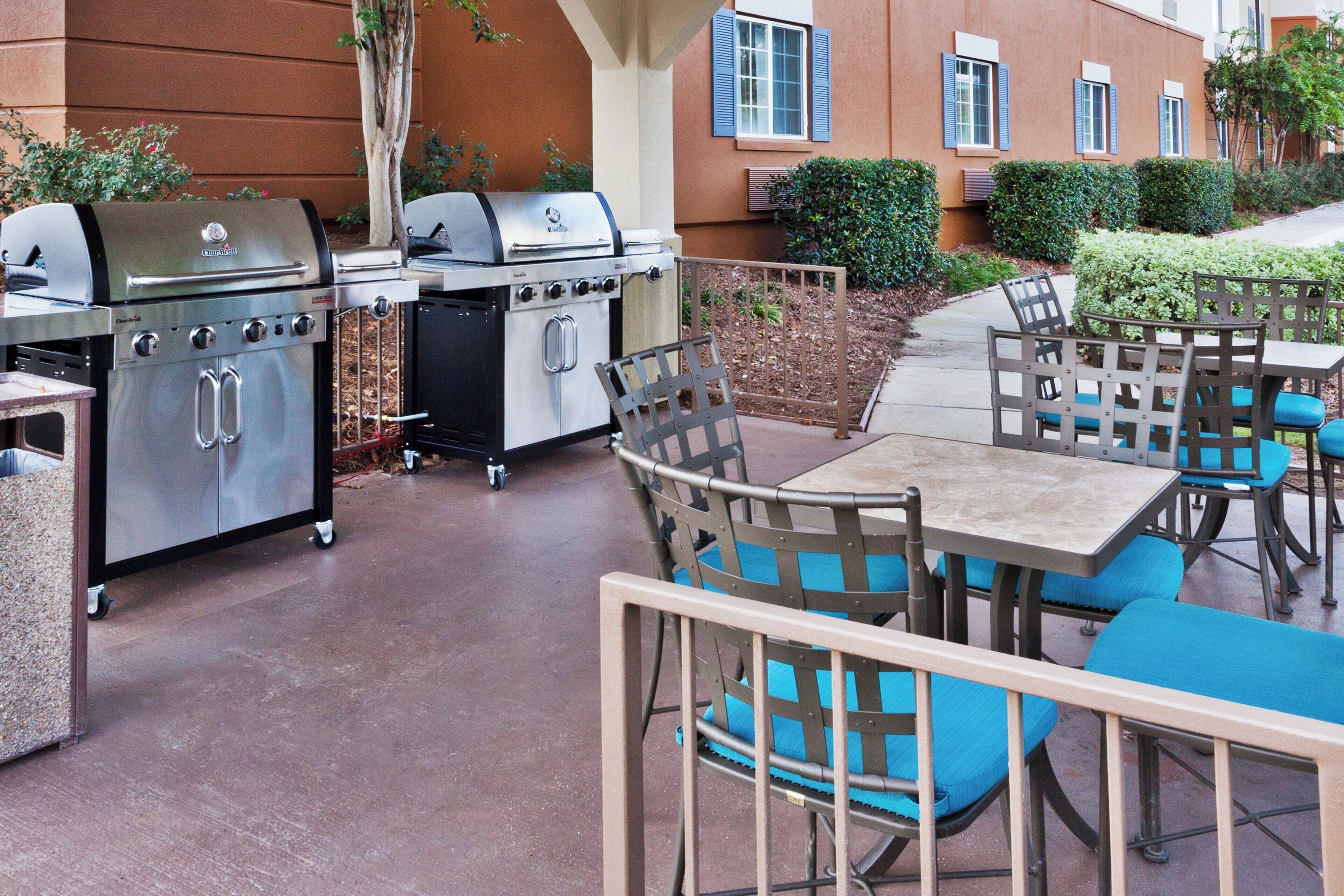 Eine Terrasse im Freien mit Grill, tragbarem Ofen und Sitzgelegenheiten mit blauen Kissen.