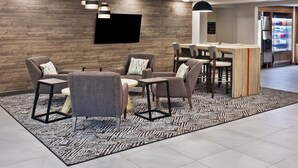 A modern reception area with a wooden wall, a flat-screen TV, and a bar area with stools.