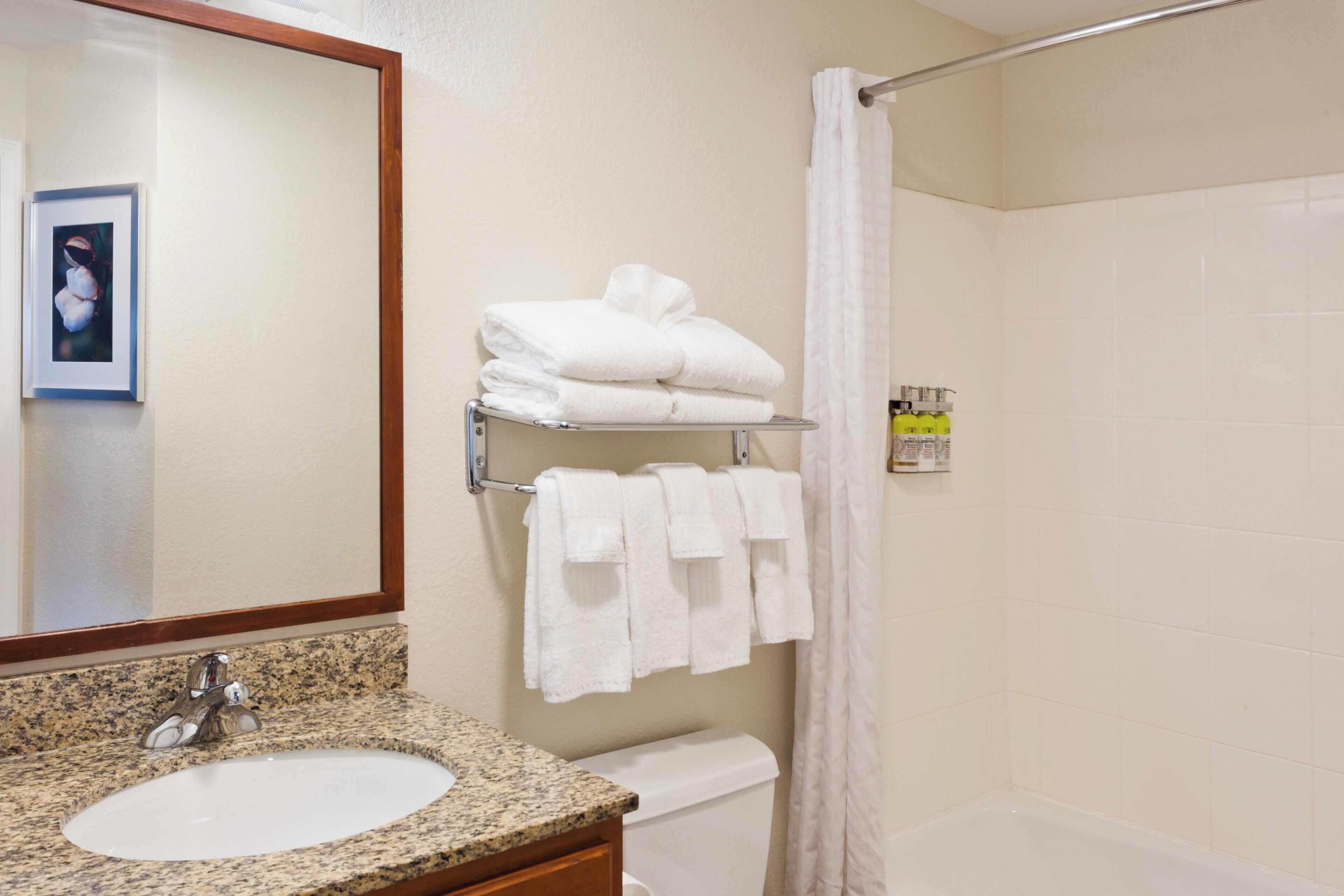 A bathroom with a sink, mirror, towel rack, and shower curtain.