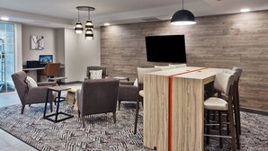 A modern interior with a bar area, seating, a flat-screen TV, and a patterned carpet.
