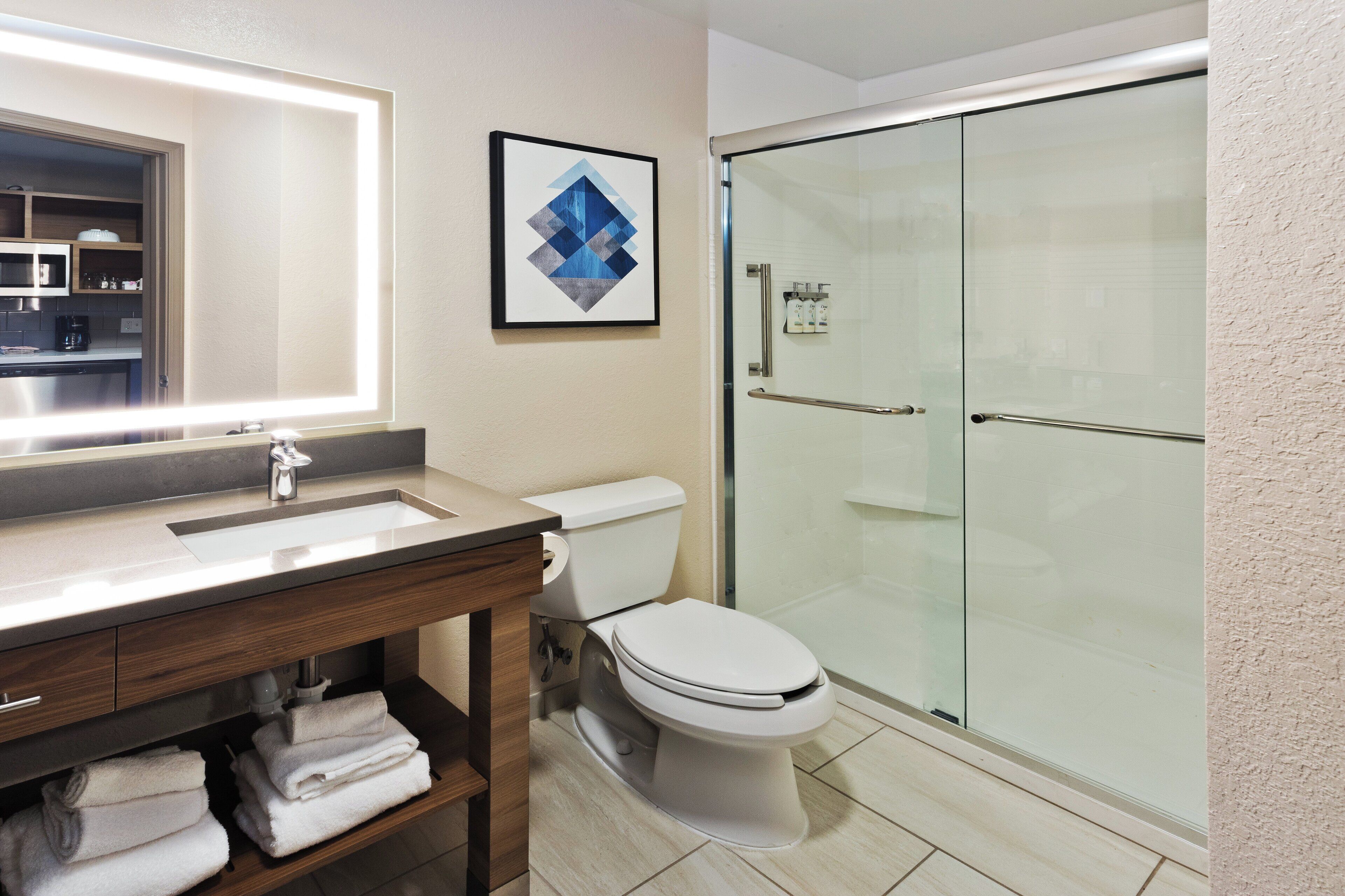A modern bathroom with a glass-enclosed shower, a white toilet, and a vanity with a mirror and sink.