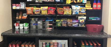 A snack and drink display with various packaged snacks, chips, and a refrigerated drink cooler.
