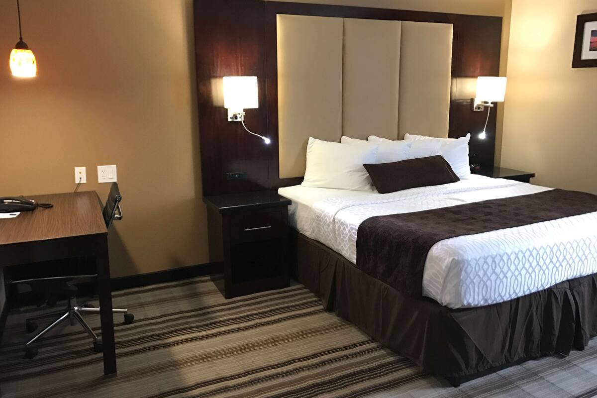 Ein Hotelzimmer mit einem großen Bett, einem Schreibtisch und zwei Nachttischlampen.