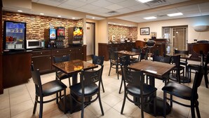 Un restaurante con decoración de madera, una barra con dispensadores de bebidas y varias mesas y sillas.