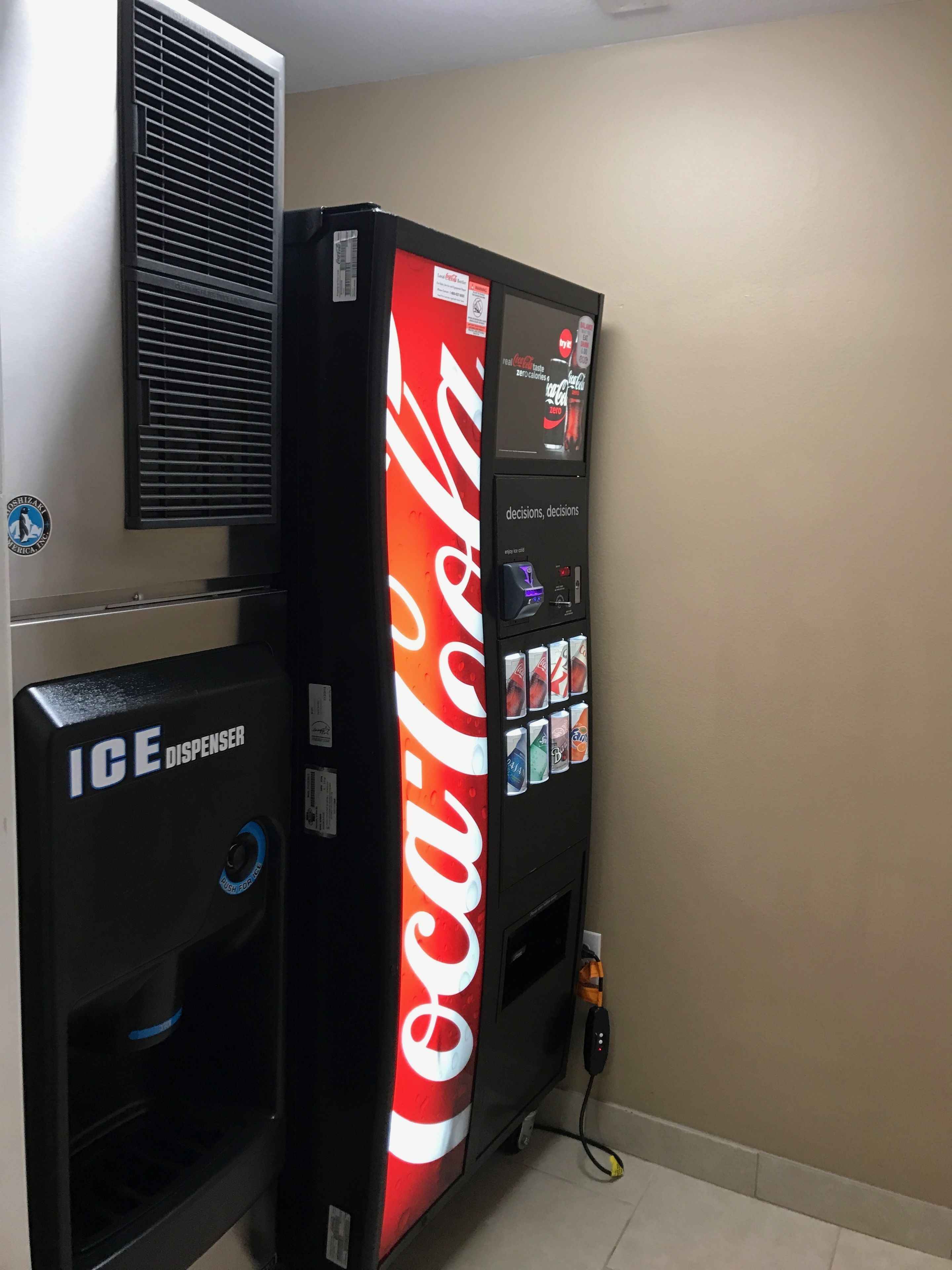A vending machine with a Coca-Cola logo, an ICE dispenser, and a digital display.