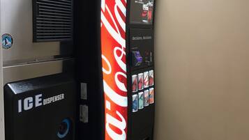 Máquina expendedora con logotipo de Coca-Cola, dispensador de hielo y pantalla digital.