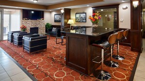 Un vestíbulo de hotel con zona de bar, asientos y chimenea.