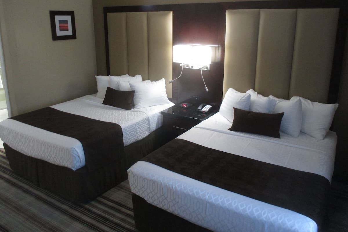 Ein Hotelzimmer mit zwei Einzelbetten, einem Nachttisch, einer Lampe und einem gerahmten Bild an der Wand.