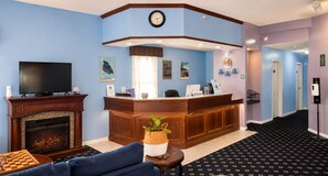 Un vestíbulo de hotel con mostrador de recepción, chimenea, televisor y zona de estar.