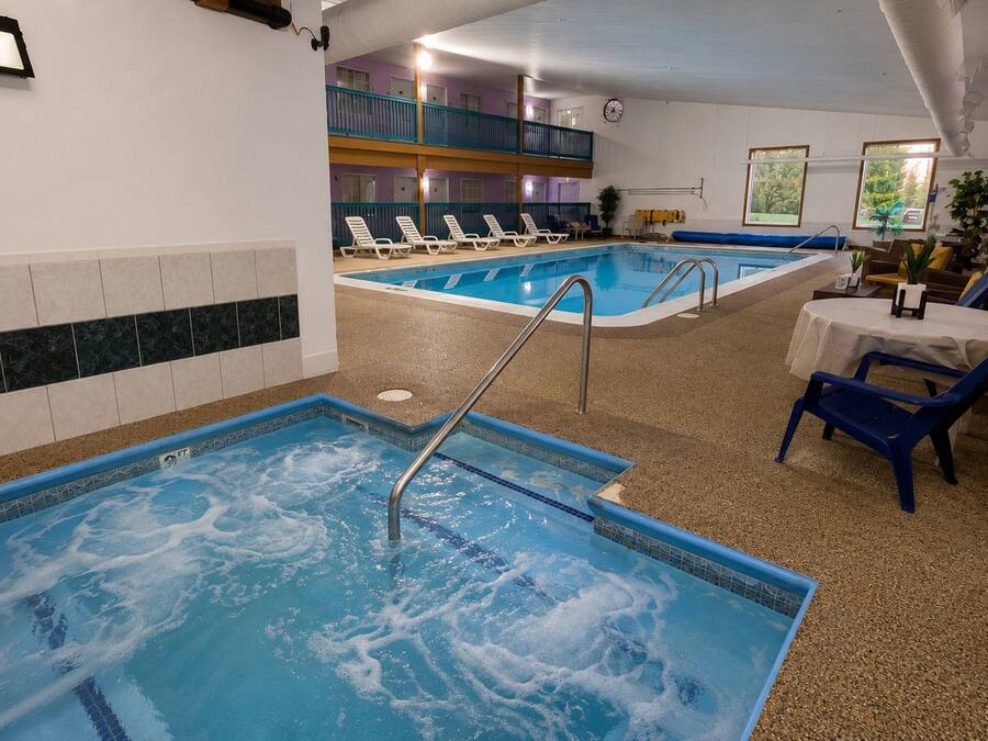 Ein Innenpool mit zwei Bereichen, Liegestühlen und einem Tisch mit Stühlen.