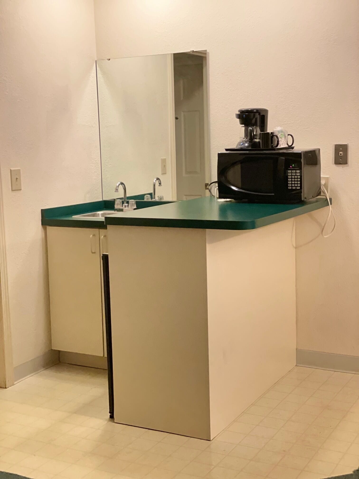 A small kitchenette with a microwave, coffee maker, and sink.
