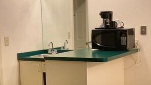 A small kitchenette with a microwave, coffee maker, and sink. - Up North Hotel (formerly Voyager Inn) (St Ignace)