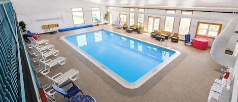 An indoor swimming pool with lounge chairs and a sunbed area.