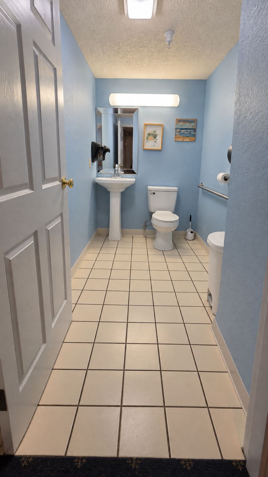 A bathroom with a white sink, toilet, and a mirror.