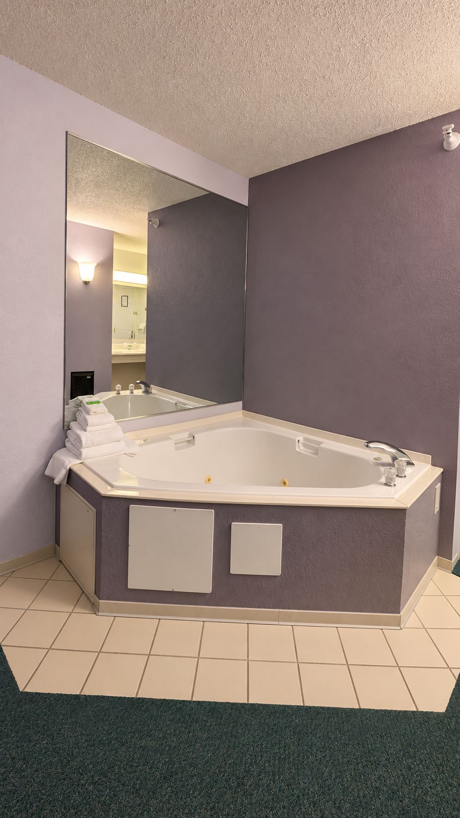 A bathroom with a large bathtub, a mirror, and a towel rack.