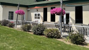 A building with a green roof, a covered patio area, and a white fence. - Up North Hotel (formerly Voyager Inn) (St Ignace)
