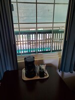 Una habitación con ventana que da a una zona de piscina, una cafetera y una taza sobre una bandeja.