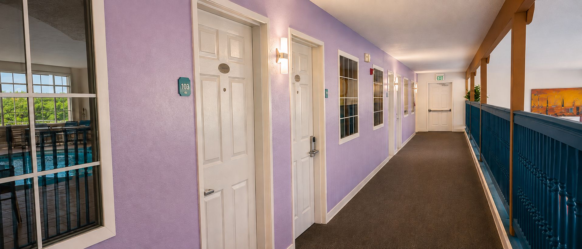 A hallway with doors, a pool view, and a balcony.