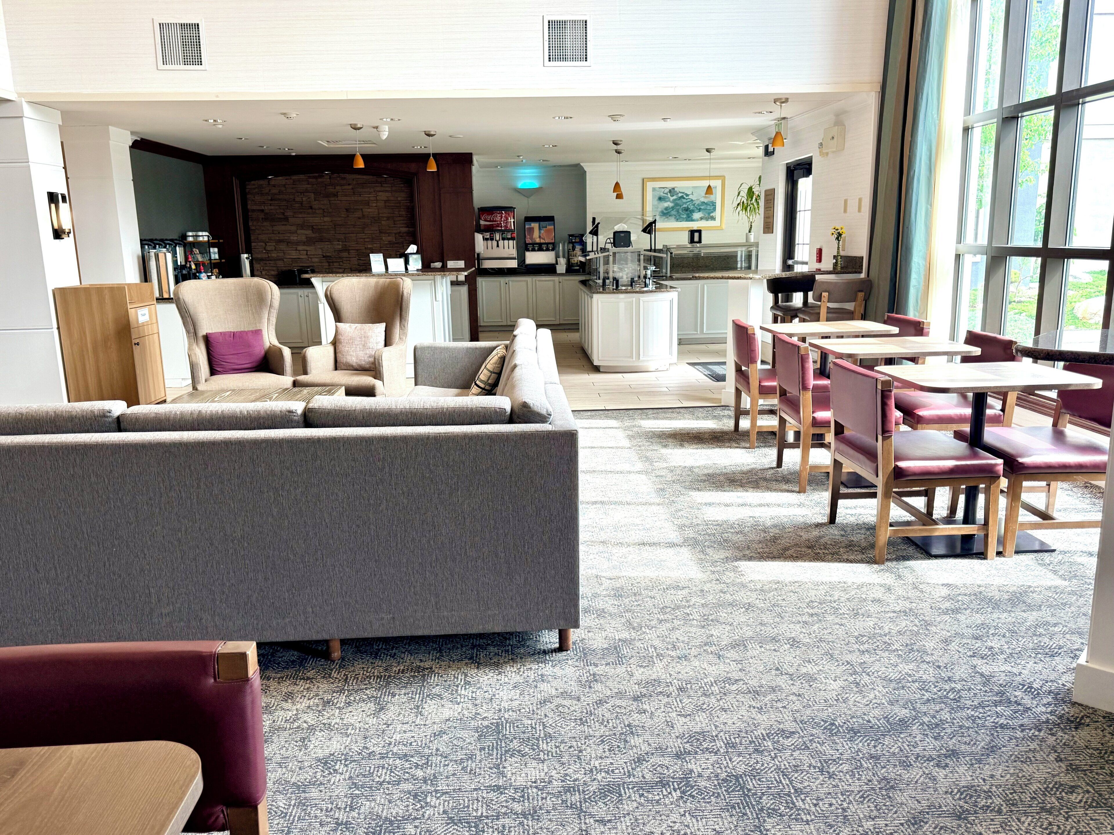 A spacious living area with a sofa, chairs, a dining table, and a kitchen in the background.