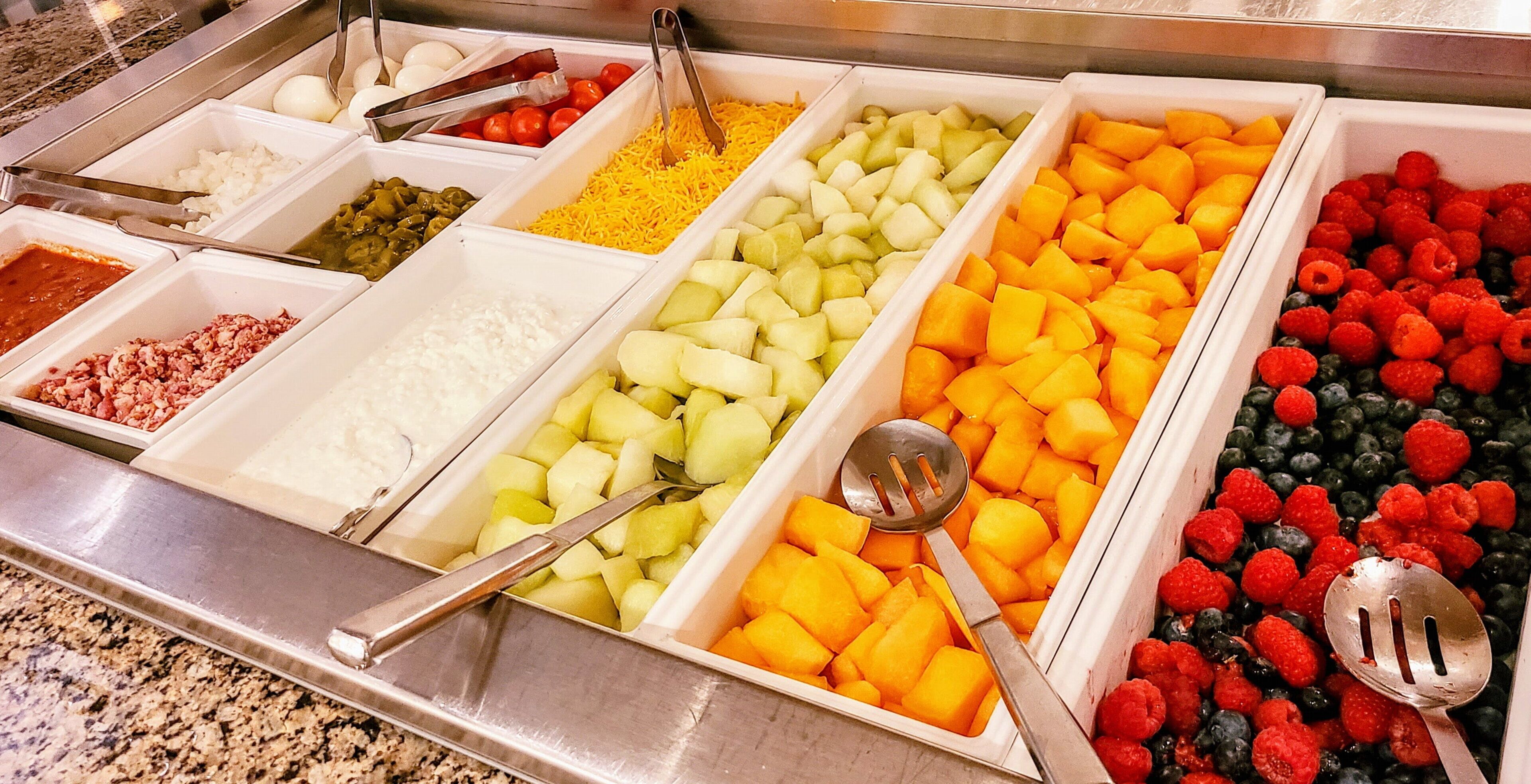 A buffet with various food items including meats, cheeses, fruits, and vegetables.