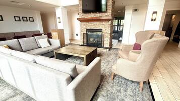 A spacious living room with a stone fireplace, a flat-screen TV mounted on the wall, and a large sectional sofa.