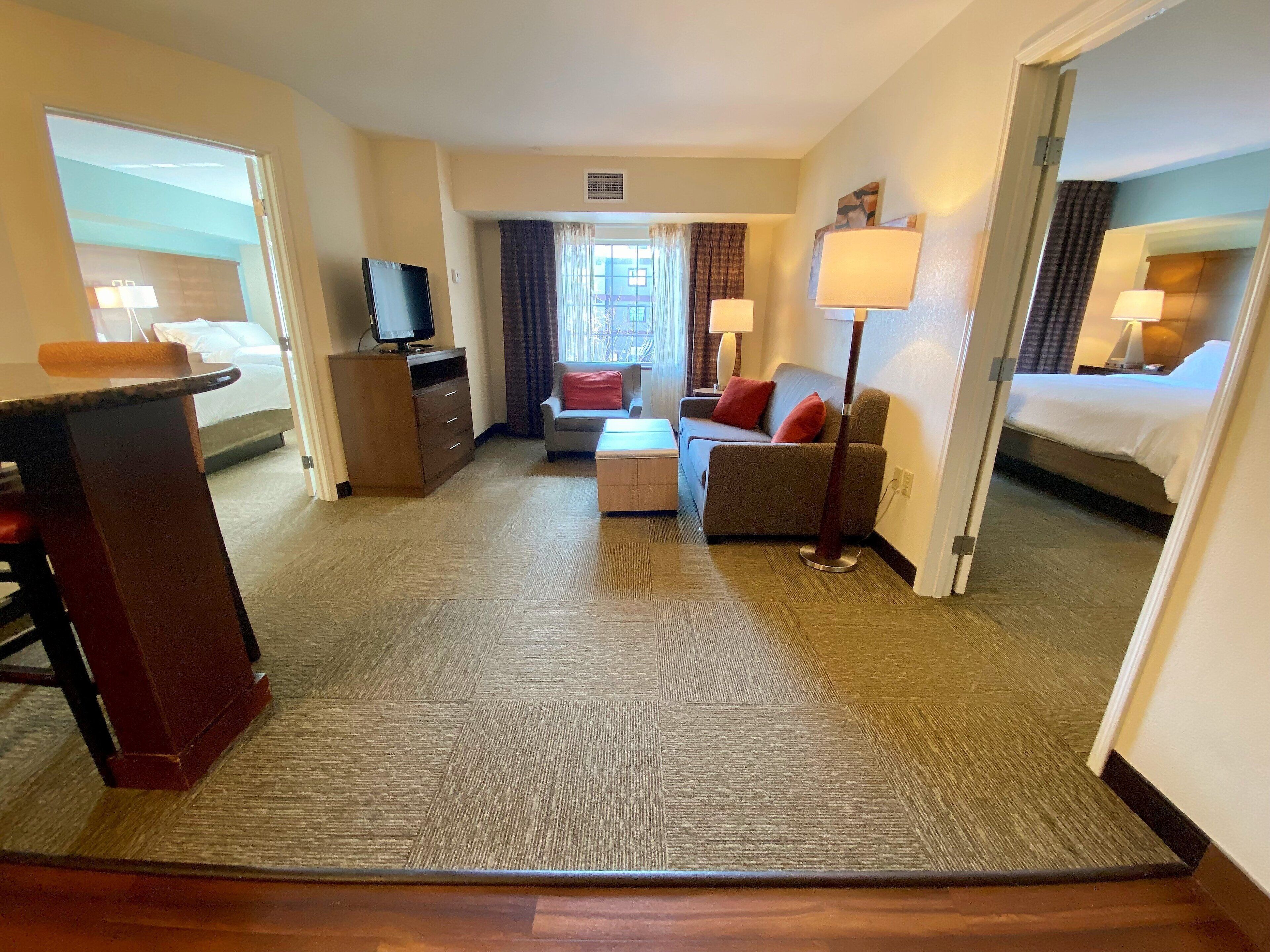 Una habitación de hotel con cama, sofá, escritorio, televisor y lámpara.