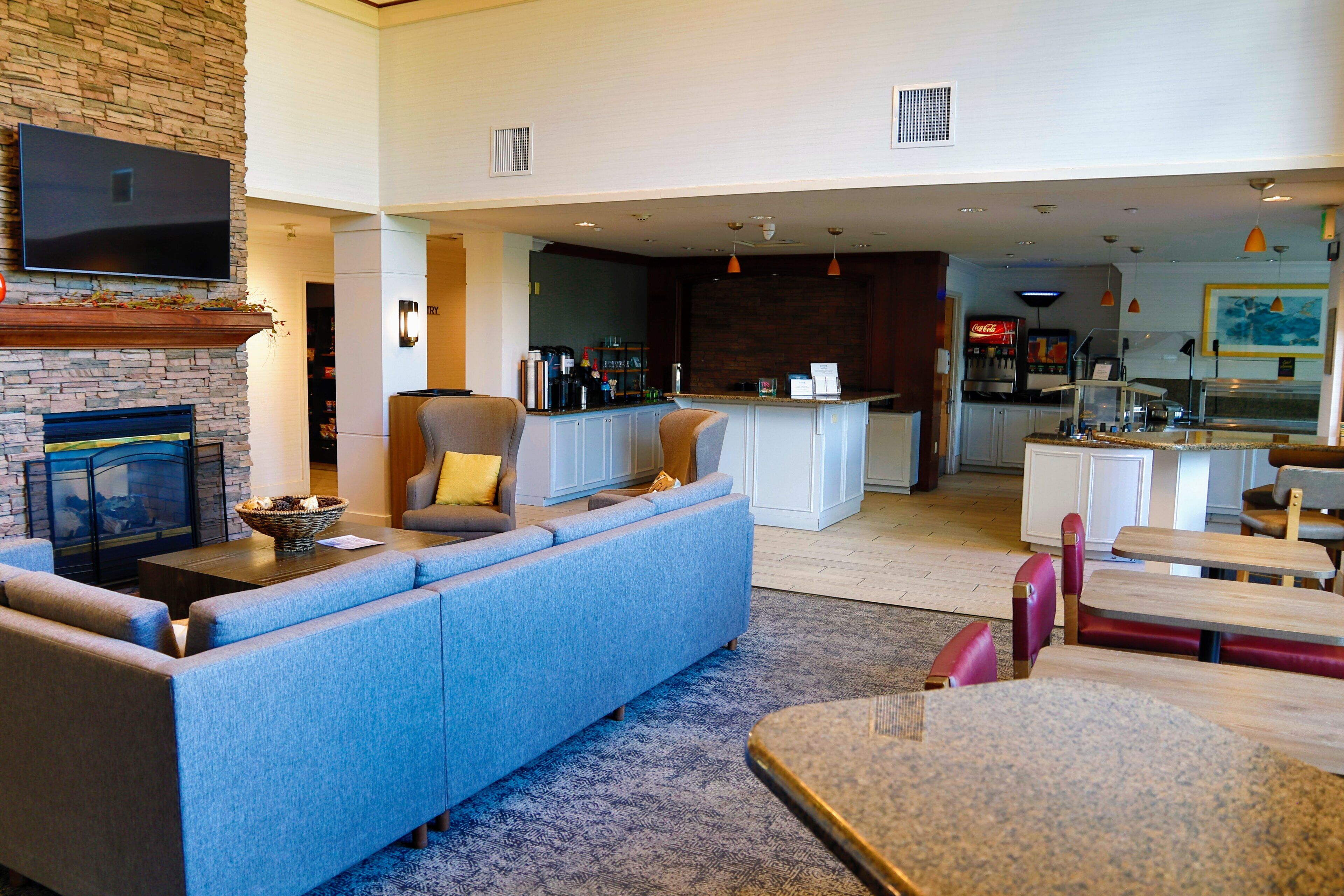 Una sala de estar moderna con un sofá azul, una chimenea y una cocina al fondo.