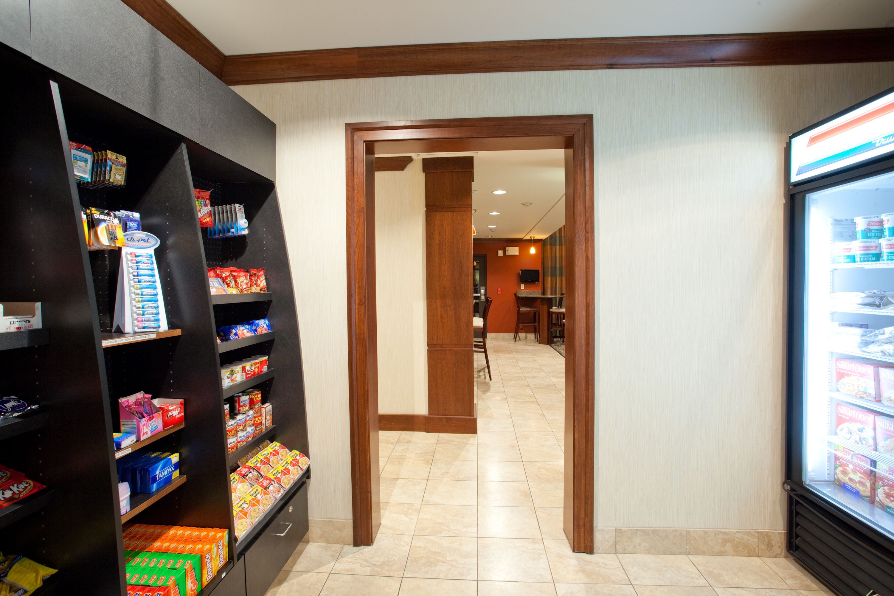 A corridor with shelves stocked with snacks and a refrigerator on the right.