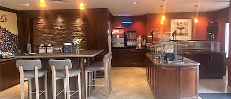A bar area with a stone wall, bar stools, and a coffee machine.