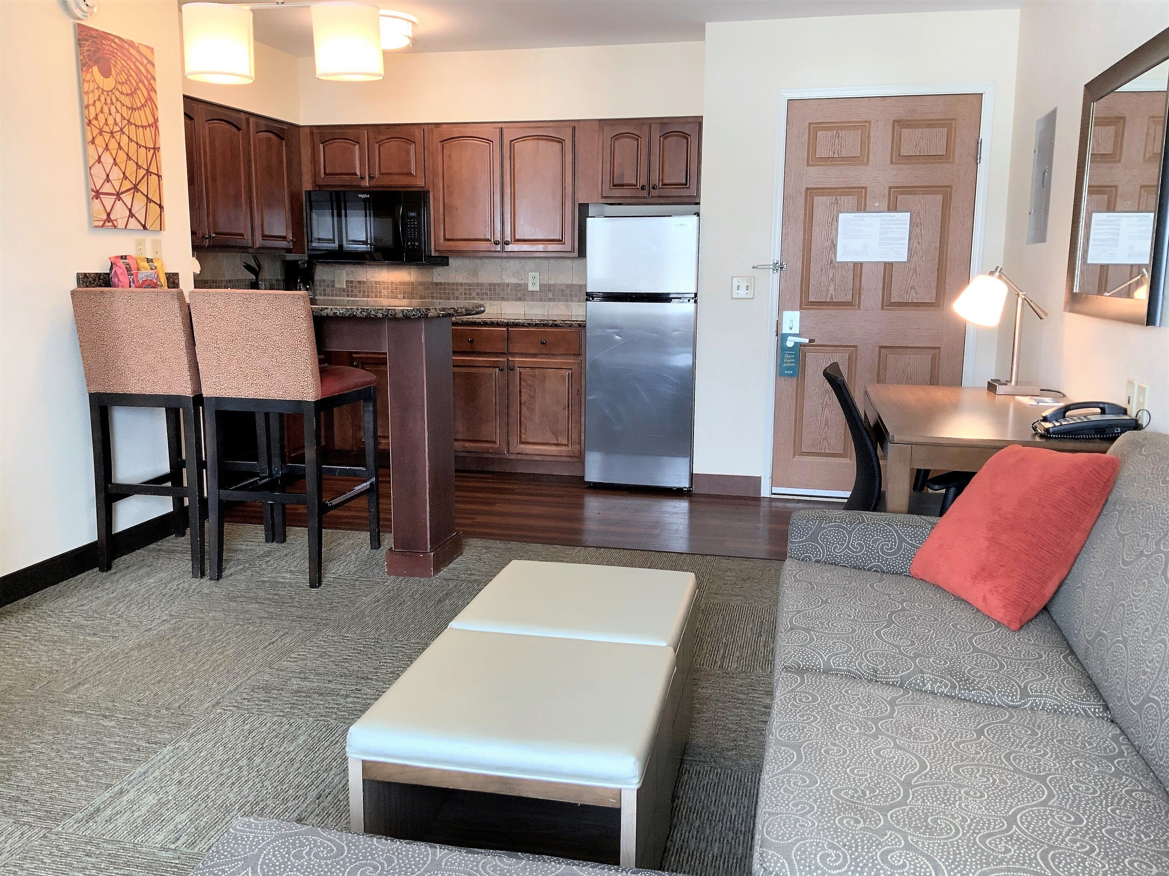 A compact kitchen with dark wood cabinets, a stainless steel refrigerator, and a microwave.