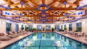 A large indoor swimming pool with wooden beams and a central decorative element.