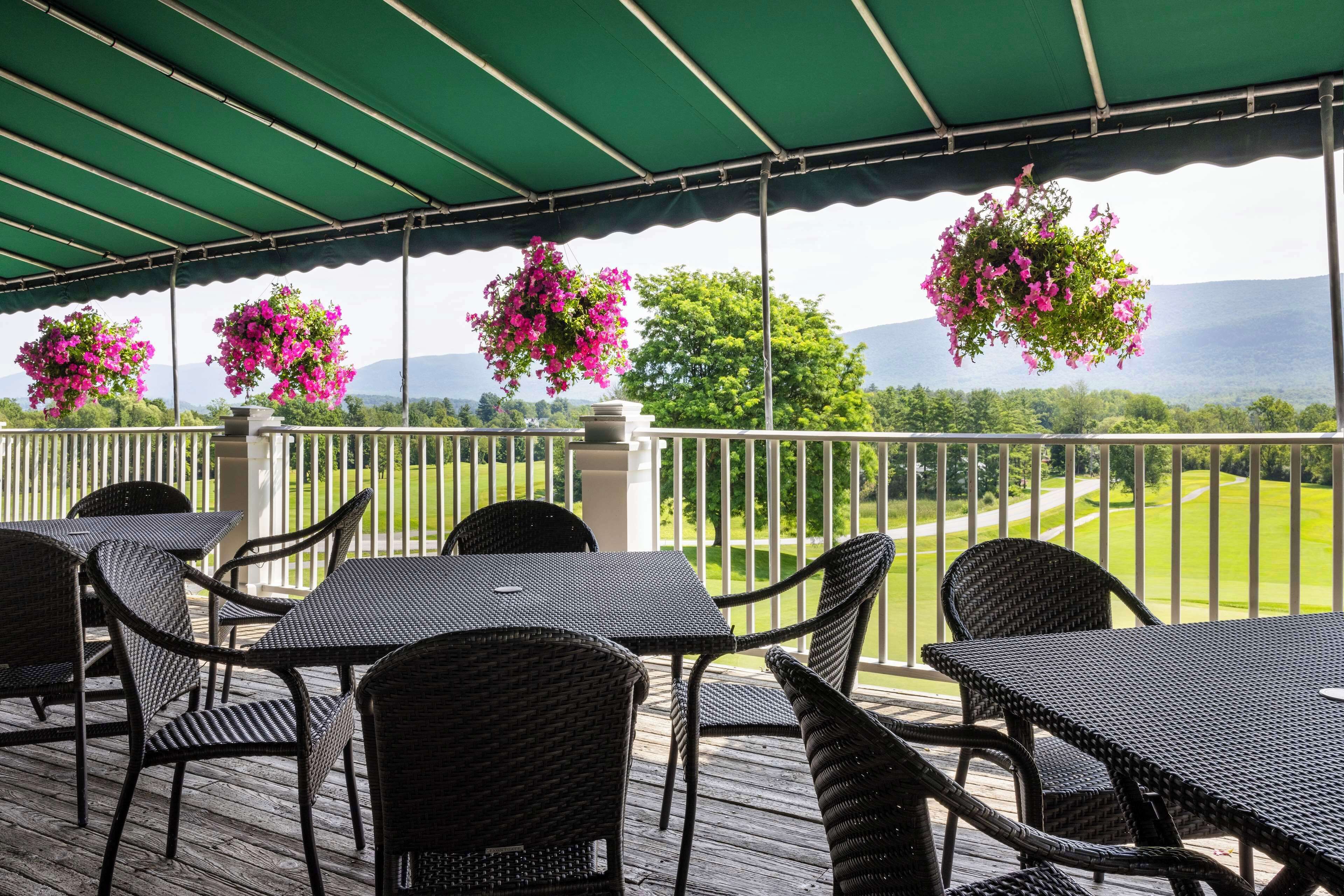 An outdoor patio with wicker furniture and hanging flower baskets.