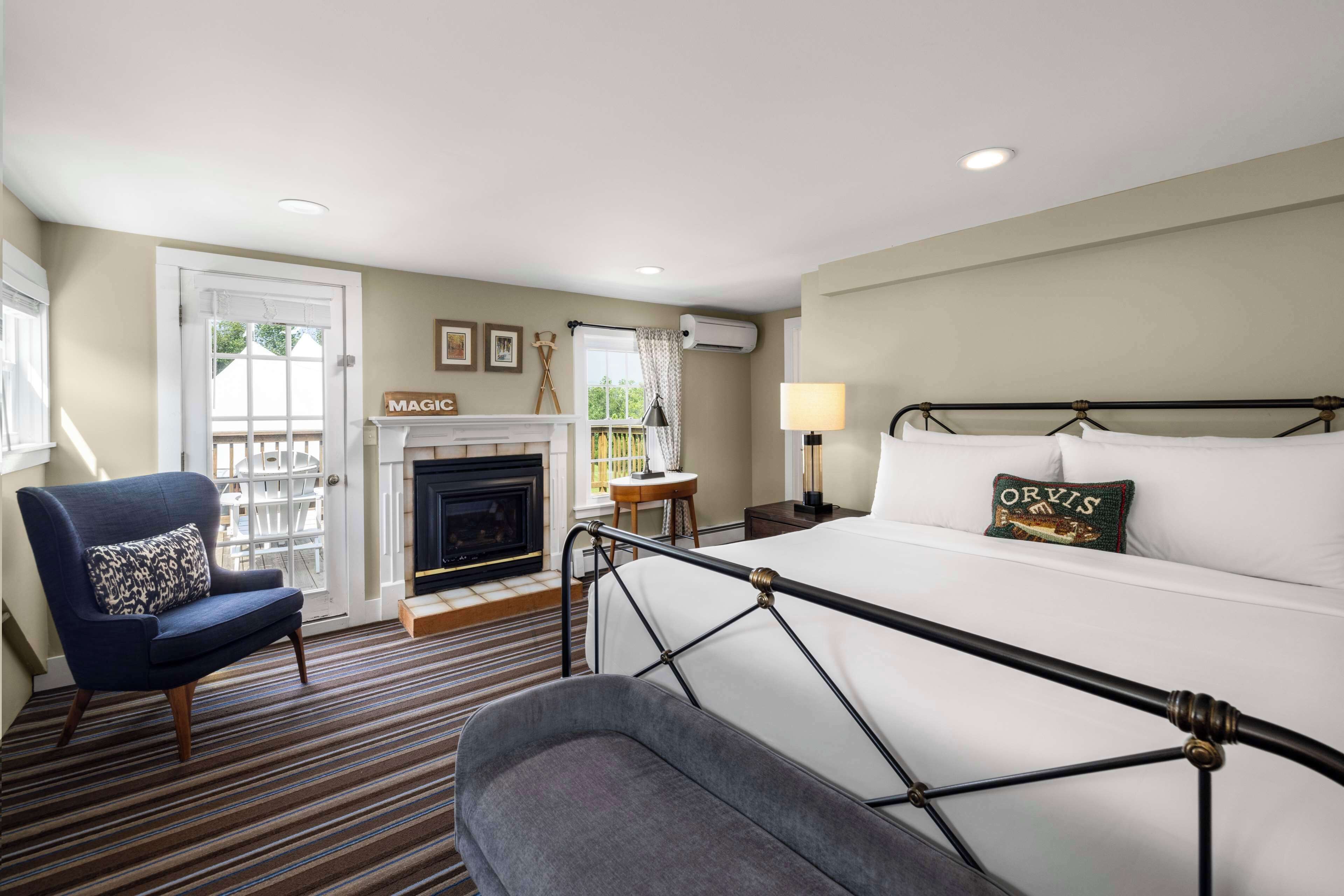 A hotel room with a bed, a chair, a fireplace, and a view of the outside.