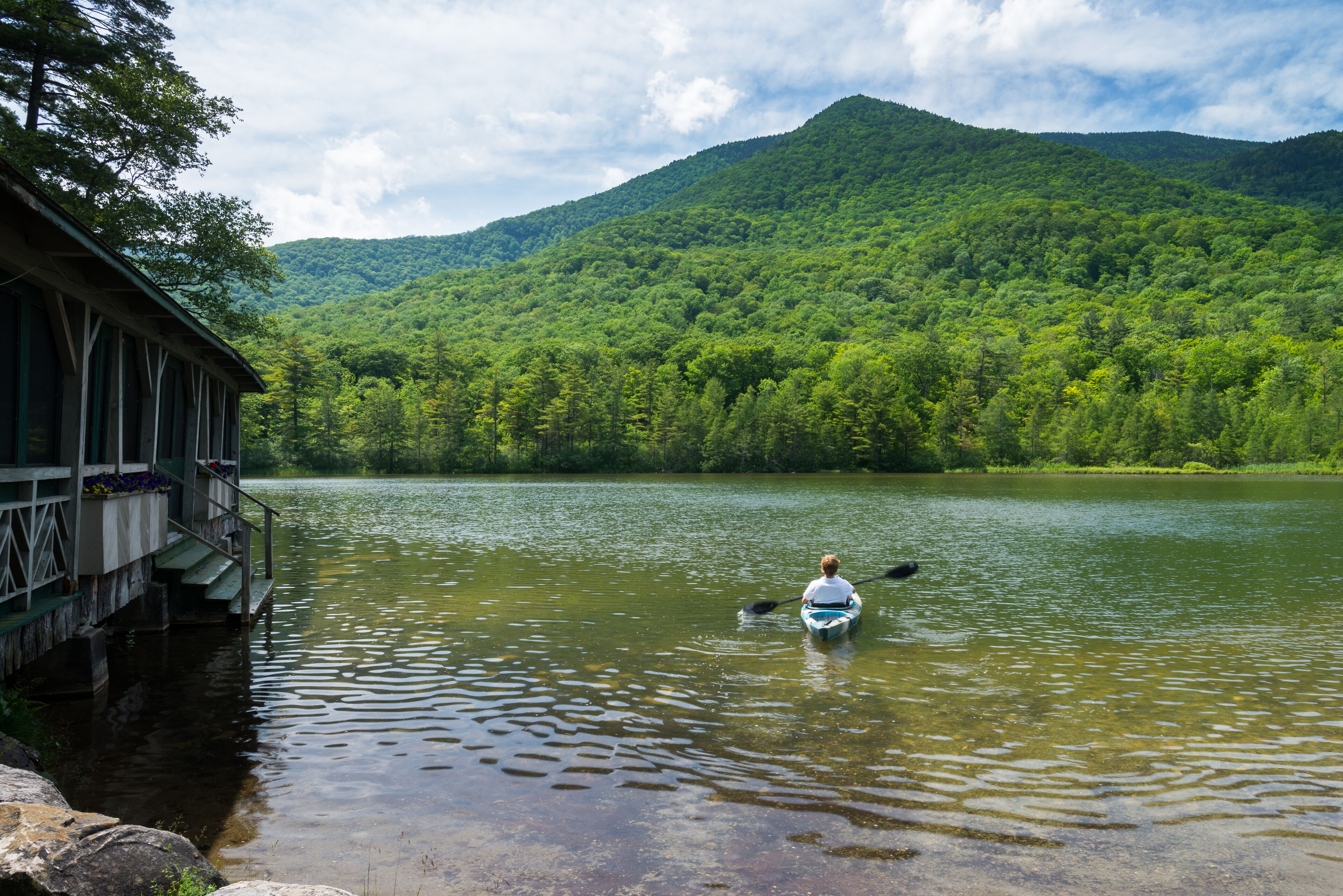A cabin by a lake with a person kayaking.
