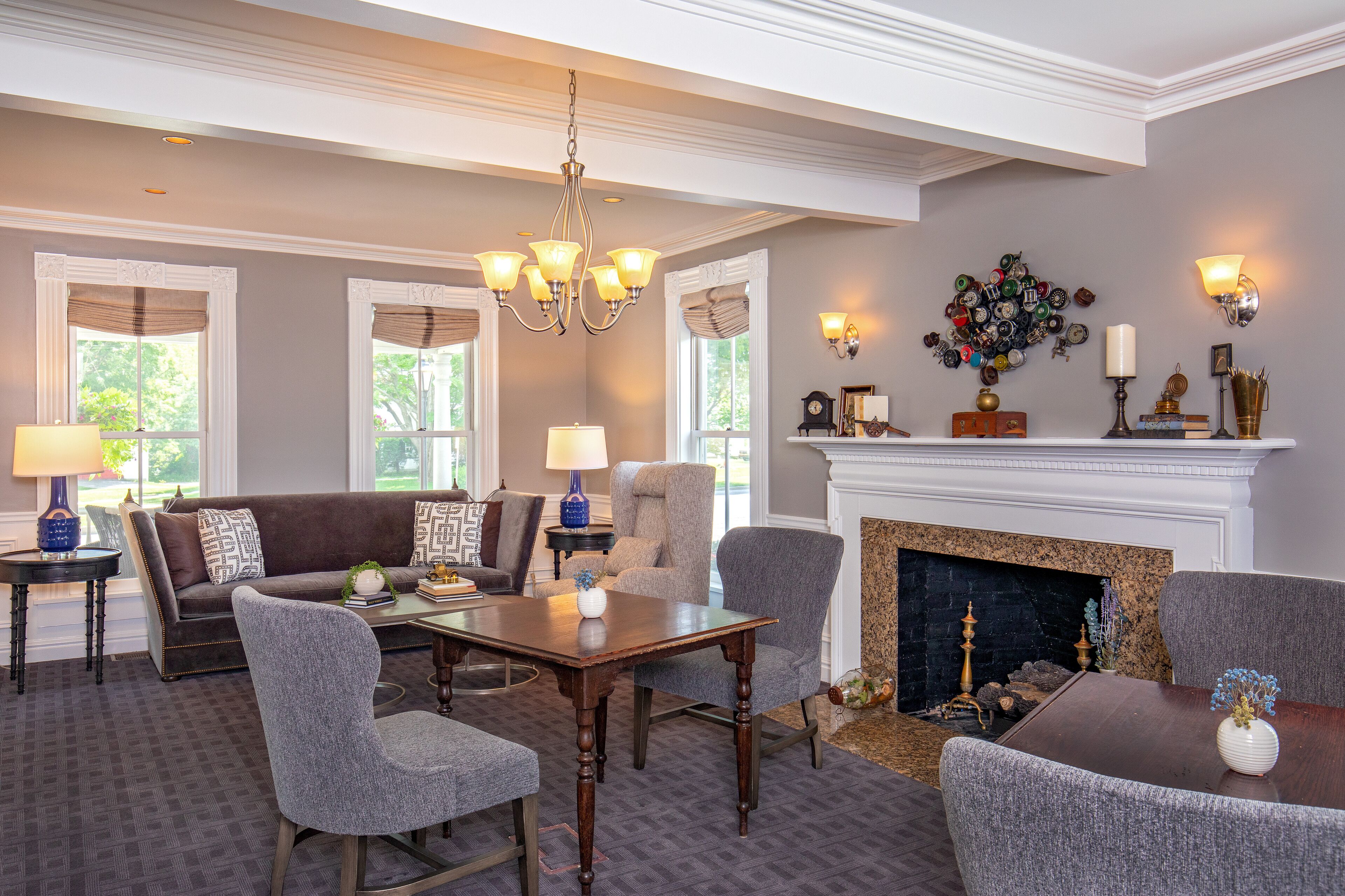 A spacious living room with a fireplace, a chandelier, and a collection of decorative items on the mantel.