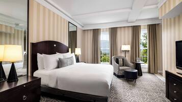 A hotel room with a large bed, a TV, a chair, and a small table.