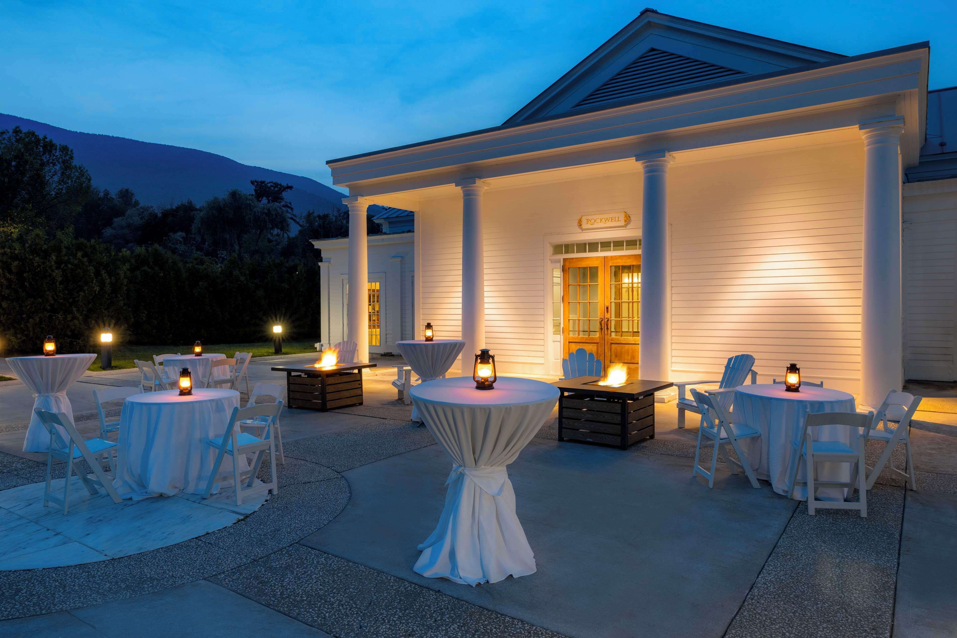 An outdoor patio with round tables and chairs, a covered seating area, and a building with a sign reading "POCKWELL".