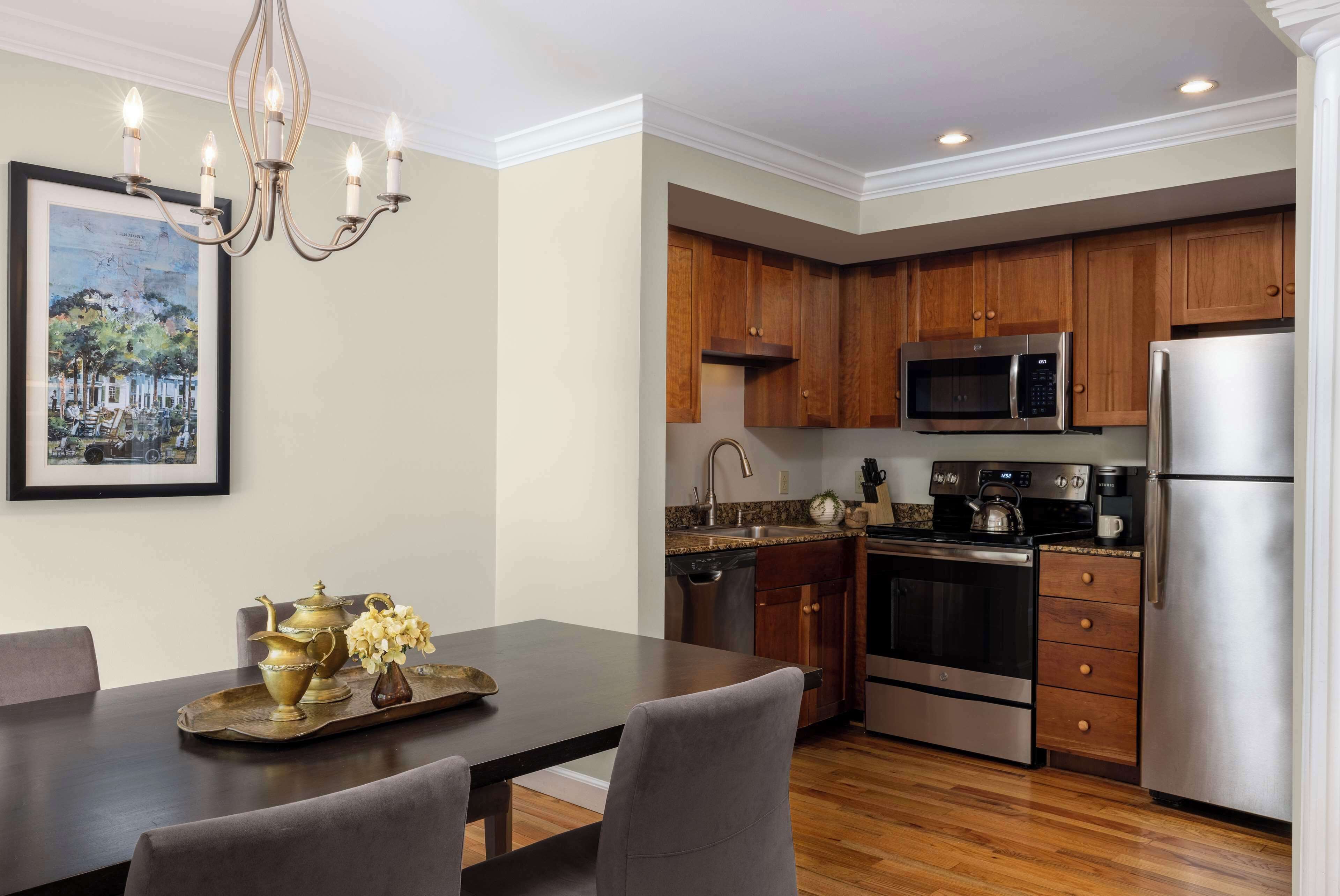 A modern kitchen with wooden cabinets, stainless steel appliances, and a dining area with a dark table and chairs.